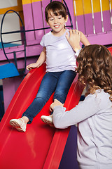 Image showing Teacher Assisting Girl While Playing On Slide