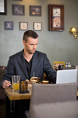 Image showing Business Man Using Laptop While Having Sandwich