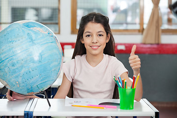 Image showing Schoolgirl Gesturing Thumbs Up At Desk