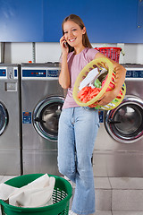 Image showing Woman Carrying Clothes Basket While Using Mobilephone