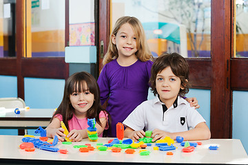 Image showing Cute Friends With Blocks On Desk In Classroom