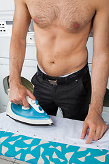 Image showing Shirtless Man Ironing Shirt On Table