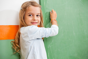 Image showing Girl Looking Away While Writing On Chalkboard In Classroom