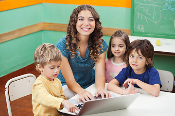 Image showing Beautiful Teacher And Students With Laptop In Classroom