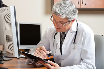 Image showing Doctor Reading While Sitting At Desk