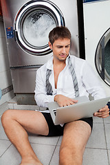 Image showing Businessman Using Laptop In Laundromat