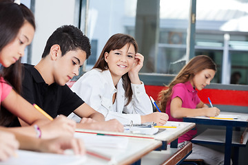 Image showing Teenage Girl With Friends Writing At Desk