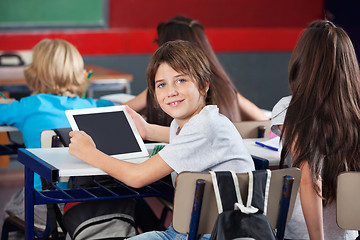 Image showing Schoolboy With Digital Tablet Sitting At Desk In Classroom