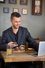 Image showing Businessman Using Laptop While Having Food In Restaurant