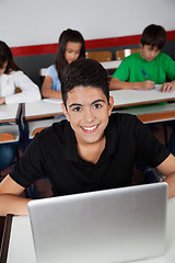 Image showing Happy Teenage Schoolboy Sitting With Laptop In Classroom