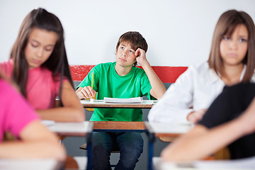 Image showing Thoughtful Teenage Male Student Sitting At Desk