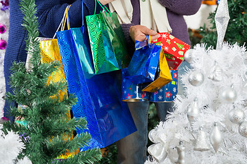 Image showing Shopaholic Couple Carrying Shopping Bags At Christmas Store