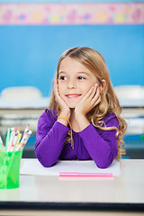 Image showing Girl Smiling While Sitting With Head In Hands At Desk