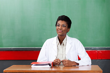 Image showing Thoughtful Female Teacher Sitting At Desk In Classroom