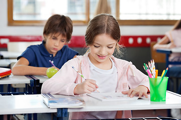 Image showing Schoolgirl Smiling While Drawing In Classroom