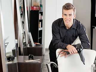 Image showing Male Hairstylist With Hairdryer Leaning On Chair