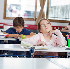 Image showing Thoughtful Schoolgirl Looking Up While Using Tablet In Classroom