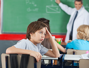 Image showing Shocked Little Boy Sitting At Desk