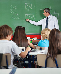 Image showing Students Sitting At Desk While Teacher Teaching In Classroom