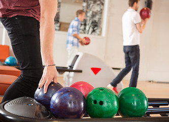 Image showing Man Picking Bowling Ball With Friends in Background