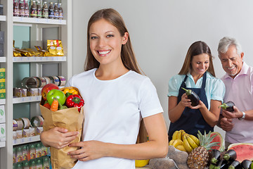 Image showing Woman Holding Grocery Bag While People Shopping In Background