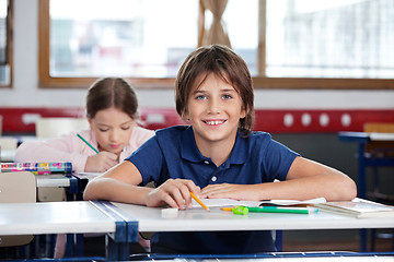 Image showing Happy Little Boy Sitting At Desk