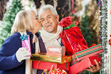 Image showing Woman Kissing Man Holding Christmas Presents