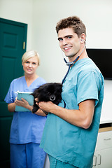 Image showing Veterinarian Doctor Carrying A Dog With Female Nurse Holding Cli