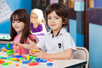 Image showing Boy With Blocks While Friends Playing In Background