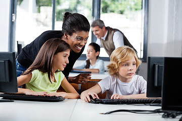 Image showing Female Teacher Assisting Schoolchildren In Using Computer