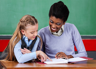 Image showing Teacher Assisting Schoolgirl At Desk