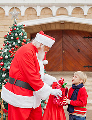 Image showing Boy Looking At Santa Claus While Taking Gift From Him