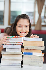 Image showing Schoolgirl Leaning On Stack Of Books In Classroom