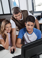 Image showing Male Teacher With Schoolchildren Using Computer At Desk