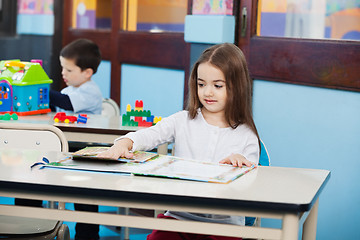 Image showing Girl Opening Popup Book at Desk