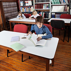 Image showing Little Boy Reading Books In Library