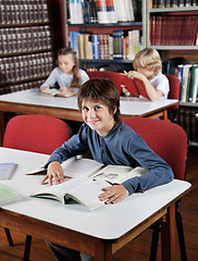 Image showing Boy Sitting At Table With Books With Classmates In Background