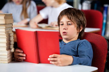 Image showing Relaxed Boy Reading Book At Table In Library