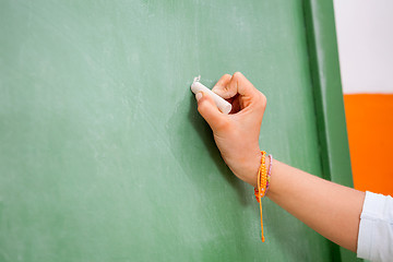 Image showing Girl's Hand Writing On Green Chalkboard In Kindergarten