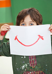 Image showing Boy Holding Painting In Front Of Face In Kindergarten