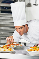 Image showing Male Chef Garnishing Pasta Dishes