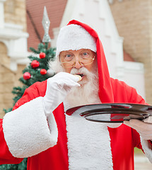 Image showing Santa Claus Eating Cookie Against House