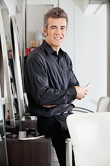 Image showing Male Hairstylist With Scissors Leaning On Cabinet