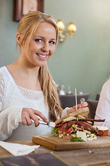 Image showing Young Woman Eating Sandwich In Restaurant