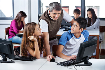 Image showing Teacher Using Computer With Students In Classroom