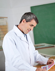 Image showing Professor Reading Paper At Desk In Lab