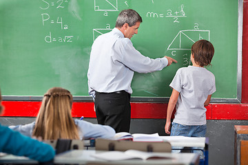 Image showing Teacher Assisting Schoolboy While Solving Mathematics