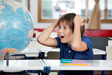 Image showing Shocked Schoolboy Looking At Globe In Classroom