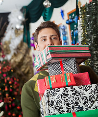 Image showing Man Carrying Stacked Christmas Gifts In Store