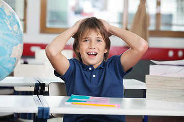 Image showing Shocked Little Boy With Globe And Books At Desk